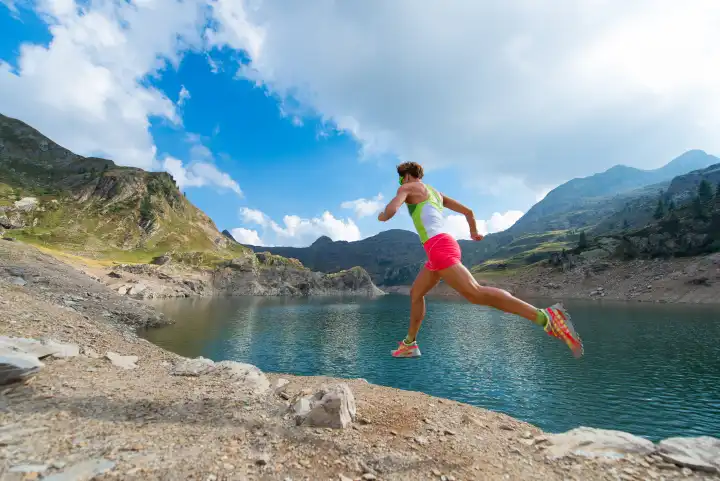 Stride of a woman who trains running near a mountain lake