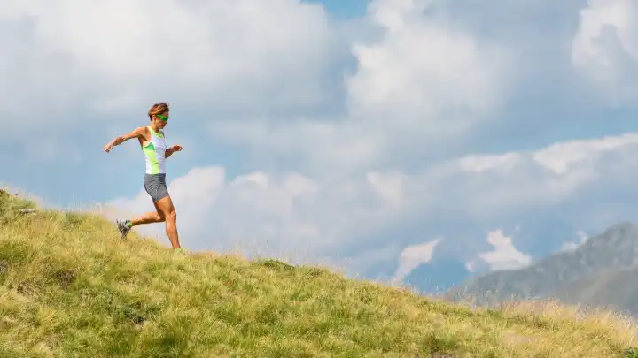 Woman runs in the mountains in the meadow alone