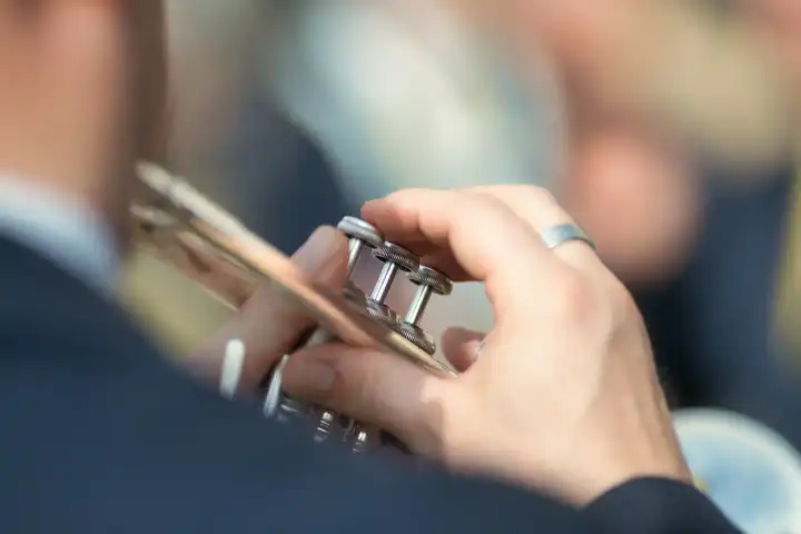 Details of hands playing the trumpet during a popular festival in northern Italy