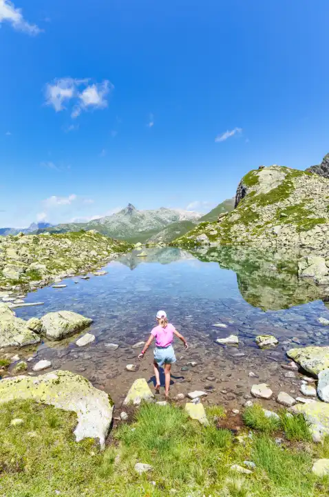 A little girl enters a small mountain lake with her feet