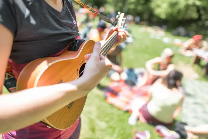 Girl plays ukulele at a party in a meadow