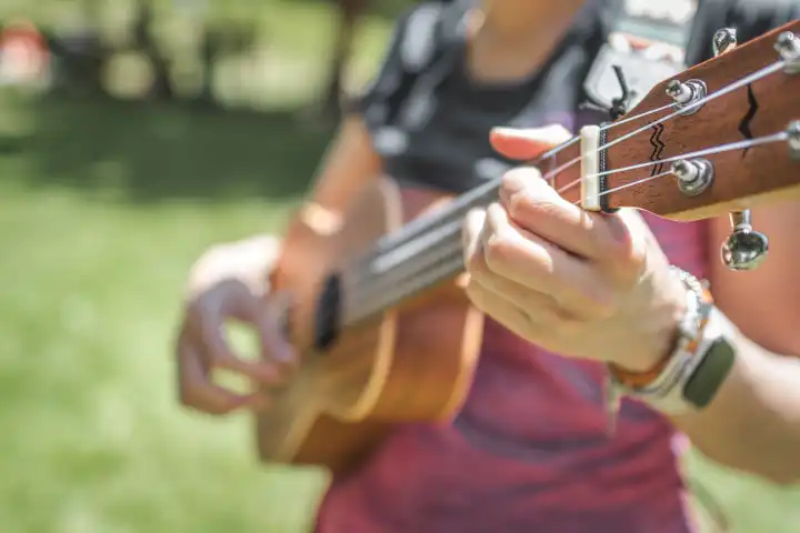 Hands of ukulele player at a party in a meadow
