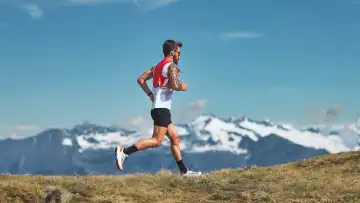A man runs runs between the mountains in the Alps