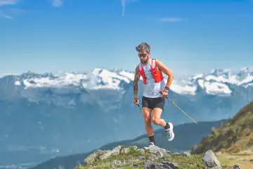 Mountain athlete with poles trains in the Alps