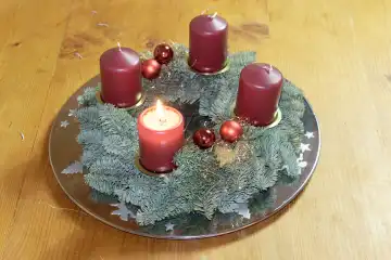 Weihnachtliche Dekoration und Symbole: Adventskranz mit einer brennenden Kerze