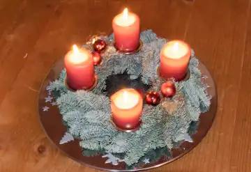 Weihnachtliche Dekoration und Symbole: Adventskranz mit vier brennenden Kerzen