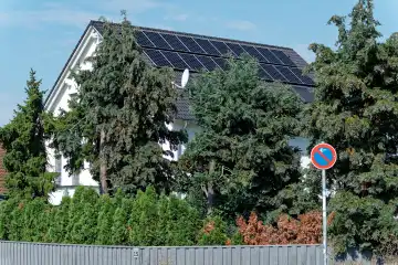 Steigende Stromkosten und Eigenproduktion von Strom, Hausdach mit Photovoltaik-Elementen