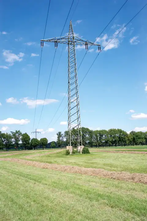 High voltage pylon on field against white blue sky