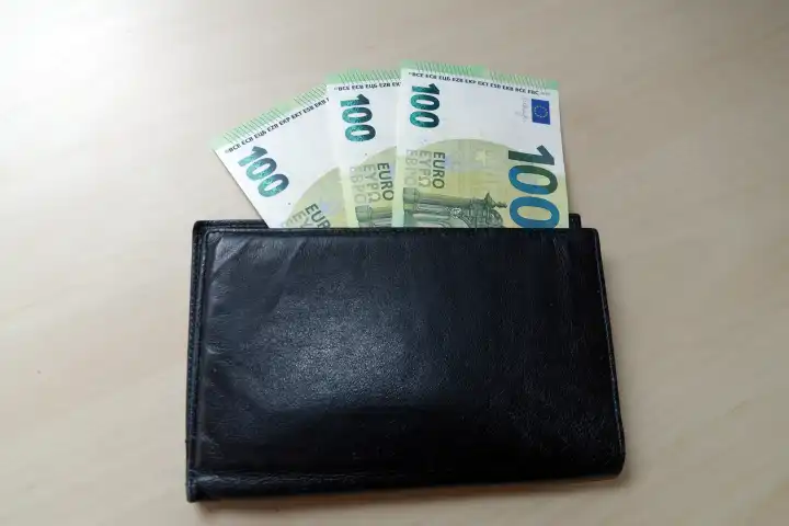 Three hundred euro bills sticking out of a wallet
