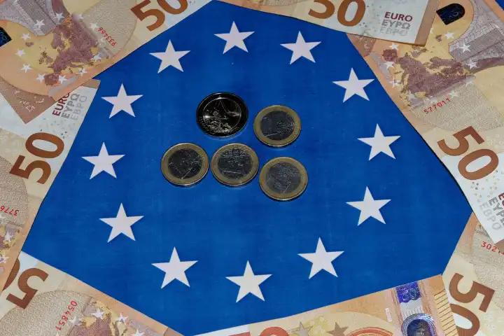 Euro-Flagge mit verschiedenen Euro-Münzen, umgeben von Euro-Banknoten