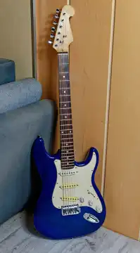 Musik, Pop, Rock: Blaue E-Gitarre, Stratocaster Form, steht an der Wand