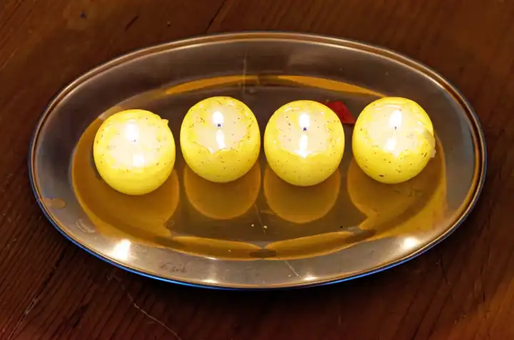 Vier brennende Kerzen auf einem silbernen Tablett