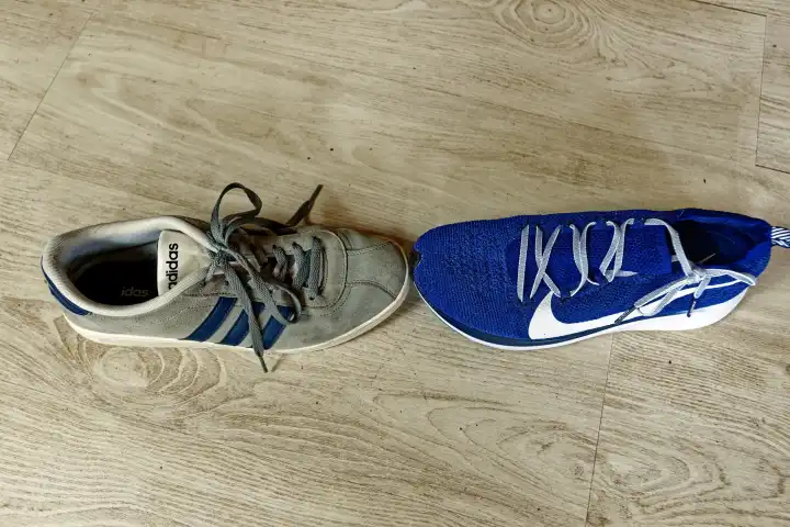 Sportschuhe von Adidas und Nike begegnen sich an der Schuhspitze