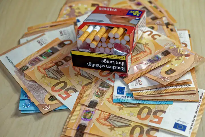 Geöffnete Zigarettenschachtel inmitten von Geldscheinen
