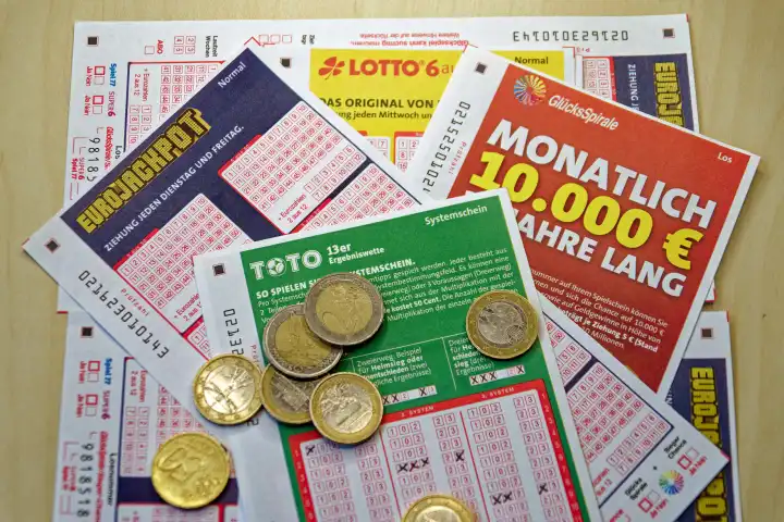 Glücksspiel, Lotto, Toto, verschiedene Tippscheine staatlicher Lotterien mit Münzen