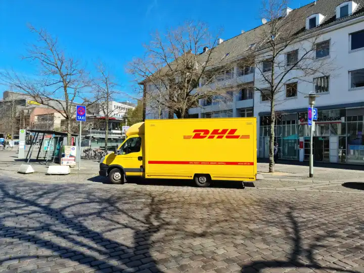 Neumünster, Deutschland - 16. April 2022: Ein gelber Lieferwagen des deutschen Paketdienstes DHL parkt bei Sonnenschein in der Stadt.
