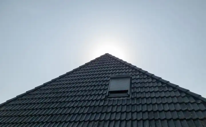 Open roof window in velux style with black roof tiles