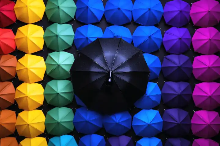 Top view on several black umbrellas and one colored umbrella, generated with AI