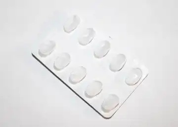 Packs of white pills packed in blisters with copy space isolated on a white background. Focus on foreground, soft bokeh. Pharmacy drugstore concept.