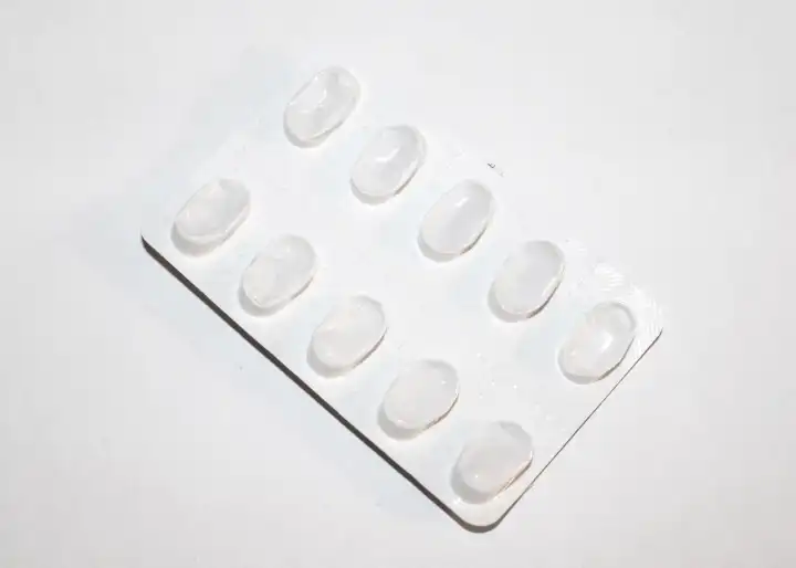 Packungen mit weißen Pillen, verpackt in Blister mit Kopierraum, isoliert auf einem weißen Hintergrund. Fokus auf Vordergrund, weiches Bokeh. Apotheke Drogerie Konzept.