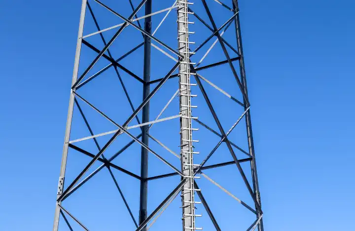 Elektrische Antenne und Kommunikationssender Turm in einer europäischen Landschaft gegen einen blauen Himmel