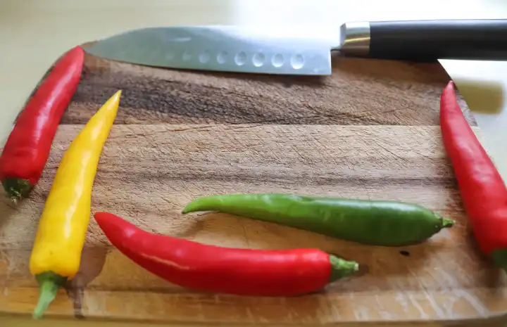Top and perspective view of chili pepper and knife on a wooden cutting board with an isolated background