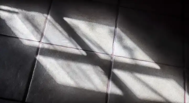 Abstraktes Konzept der weichen Schatten des Sonnenlichts durch ein Fenster auf einer Fliese Hintergrund