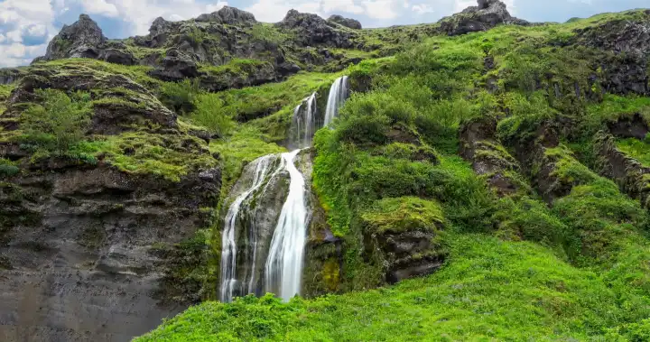 Langzeitbelichtung eines Wasserfalls in einer felsigen Landschaft in Island im Herbst