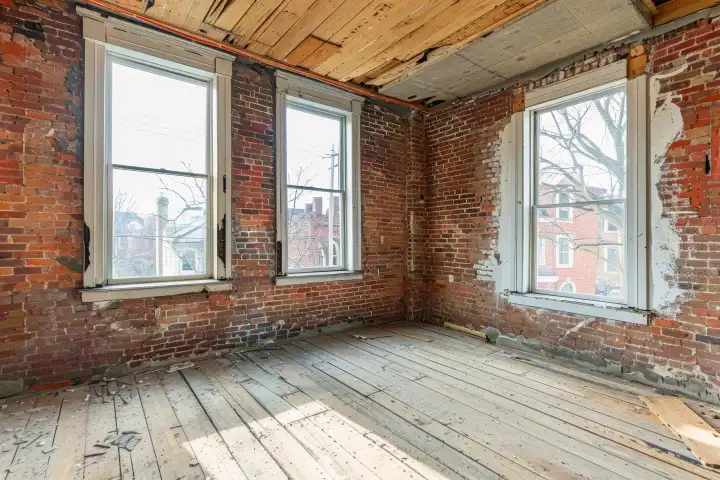 Ein teilweise renovierter Raum mit sichtbaren Ziegelwänden, neuen Fenstern und halb gestrichenen Wänden, generiert mit KI