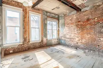 A partially renovated room with exposed brick walls new windows and half painted walls, generated with AI