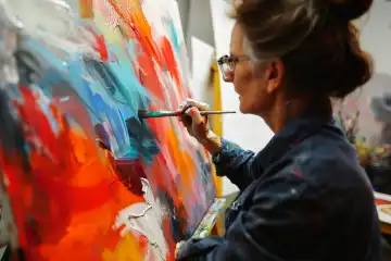 A woman painting on a large canvas with a passionate expression showcasing artistic talent and individuality, generated with AI