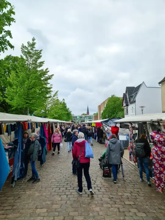 Neumünster, Deutschland - 04. Mai 2024: Menschen schauen sich auf einem Stoffmarkt mit vielen Ständen um und kaufen eifrig ein