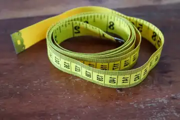 Yellow tape measure isolated on a brown wooden background. Sewing concept.