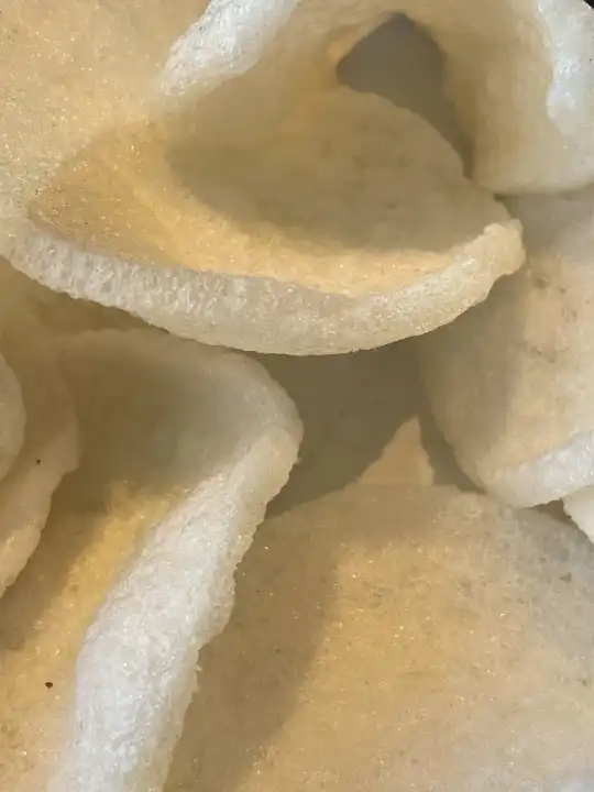 Kerupuk Udang oder Garnelencracker werden aus Tapiokamehl und fein gemahlenen Garnelen hergestellt, die mit Kräutern und Geschmacksverstärkern vermischt werden.