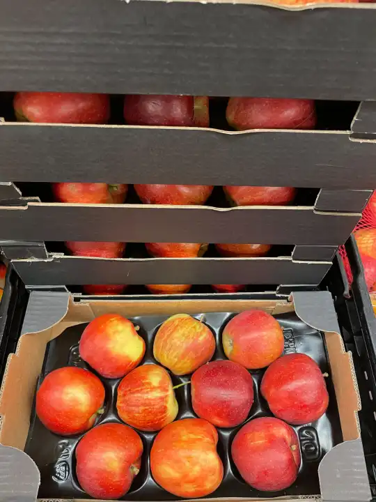 Ripe juicy red apples in a cardboard box.