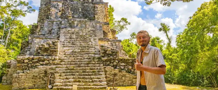 Traveler and tourist guide at the ancient Mayan site with temple ruins pyramids and artifacts in tropical natural jungle forest palm trees and walking trails in Muyil Chunyaxche Quintana Roo Mexico.