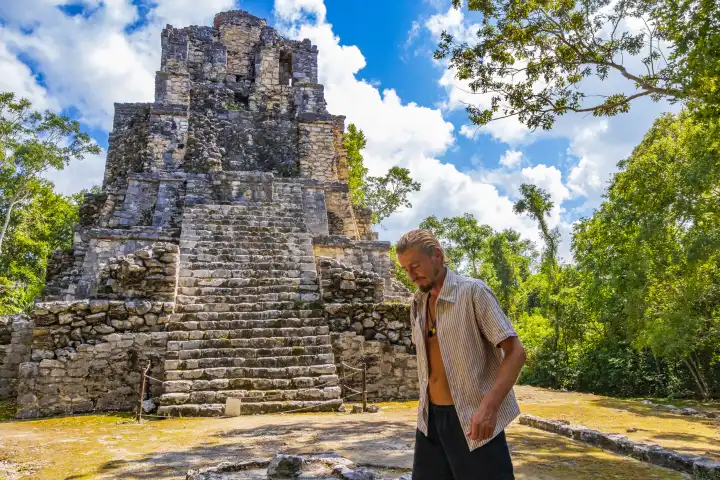 Traveler and tourist guide at the ancient Mayan site with temple ruins pyramids and artifacts in tropical natural jungle forest palm trees and walking trails in Muyil Chunyaxche Quintana Roo Mexico.