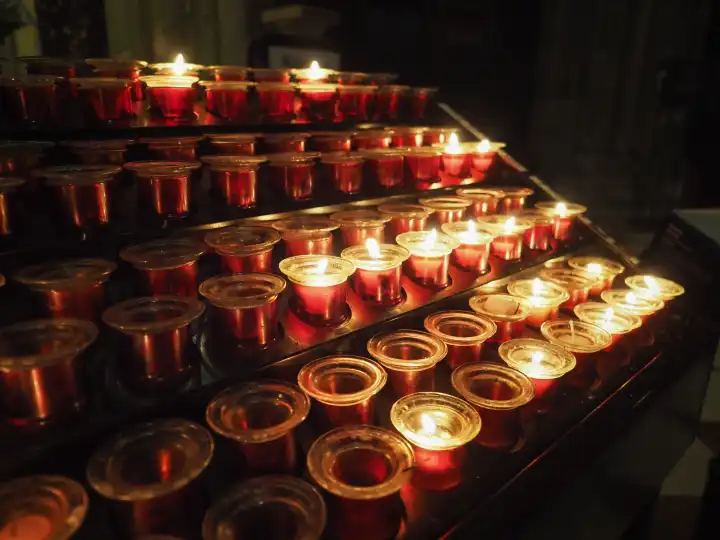 Kerzen, die von Gläubigen in einer Kirche angezündet werden