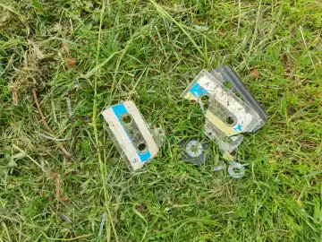 vintage broken tape cassette in the grass top view