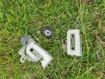 vintage broken tape cassette in the grass top view