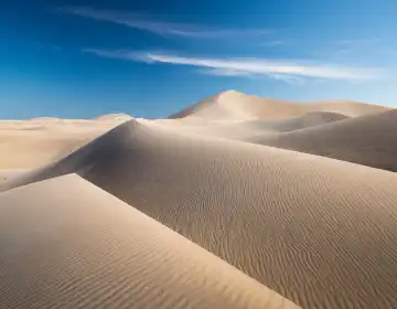 desert sand dunes and blue sky useful as a background, AI generated