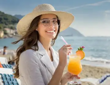 schöne Frau mit Cocktail am Strand, AI generiertes Bild