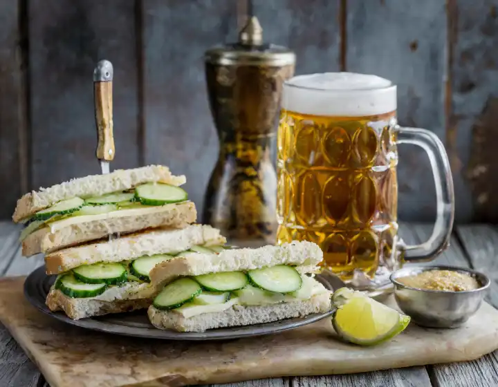Gurkensandwiches traditionelles britisches Essen mit Bier und Tee, AI generiertes Bild