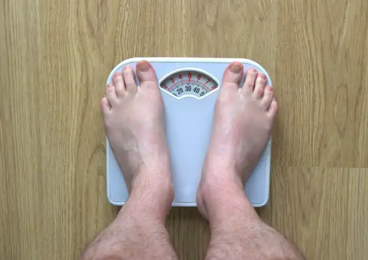 Man's feet on bathroom scales as he weighs himself