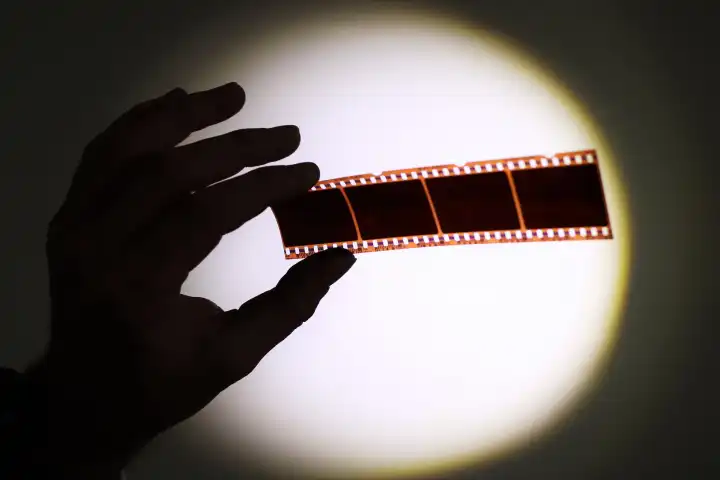 Silhouette der Hand, die 35mm fotografische Filmnegative hält