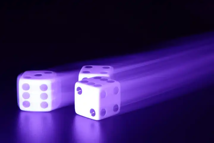 Three dice with motion blur in a purple light