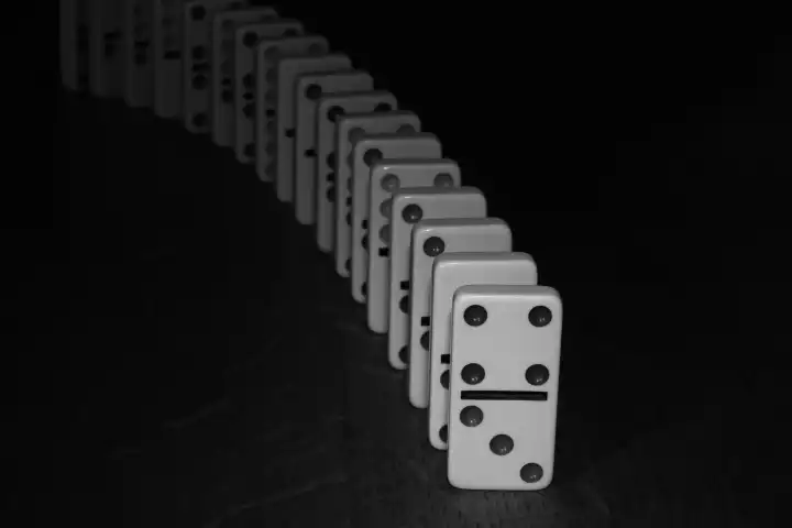 Monochrome Linie von Dominosteinen, die aus der Dunkelheit kommen