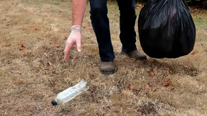 Hände und Füße der Person, die Müll in einem Park aufnimmt