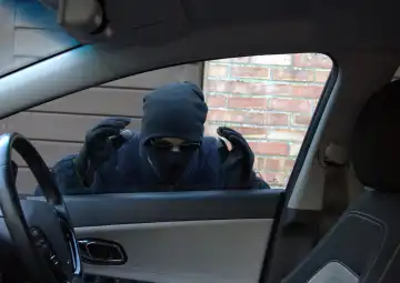 Car thief looking through a car window with intent to steal